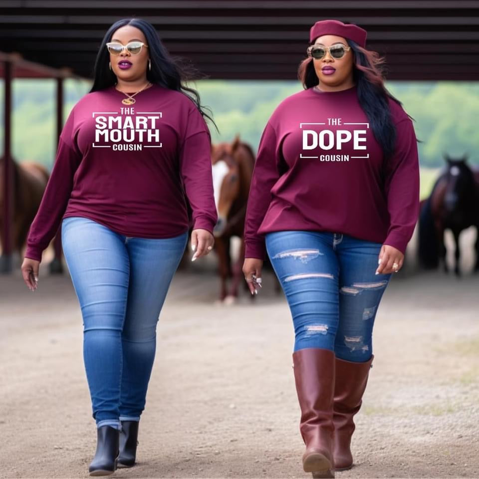 Two female cousins wearing maroon sweatshirts with text that says the smart mouth cousin and the dope cousin, walking in a stable.