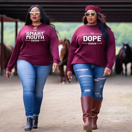 Two female cousins wearing maroon sweatshirts with text that says the smart mouth cousin and the dope cousin, walking in a stable.